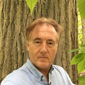Donald Davis, who will be presenting an online class about chestnut trees with Coastal Rivers Conservation Trust, stands beneath an American Chestnut tree. Courtesy of Coastal Rivers