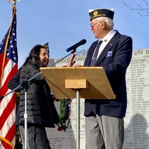 Post 54’s longtime Daughters of the American Revolution wreath-layer Clara Wentworth, 95 next month, reaches to touch Post Cmdr. William Cossette Jr.’s arm at Wiscasset’s honor roll wall Nov. 11 when Cossette remarked she was the eldest attendee. SUSAN JOHNS/Wiscasset Newspaper