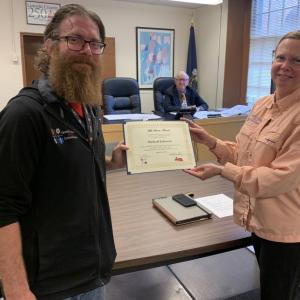 Lincoln County emergency dispatcher Mike Johnson, left, receives recognition Aug. 15 as a “life saver” from the commissioners and Communications Director Tara Doe. BILL PEARSON/Boothbay Register