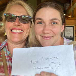 Patrisha McLean, CEO/Founder of Finding Our Voices, with Marykate Moriarty of Streetfood 330, and the proceeds of her “Into the Light!” July sales. Moriarty said “The amount of people in July who showed up just for our “Into the Light!” Mango Bango Dessert Cup was amazing.” Patrisha McLean photo
