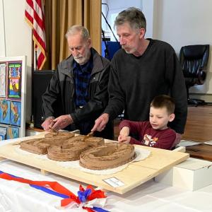 The present, past and future generations of Edgecomb cut the ceremonial cake. From left, Willis Clifford, Mike Smith, and Reid Carver. FRITZ FREUDENBERGER/Boothbay Register
