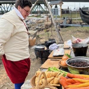 Chef Sam Collins with a table full of local ingredients and pots boiling over the fire at the 2023 17th Century Foodways event. Courtesy of Maine’s First Ship