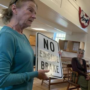 Edgecomb resident Carol Leone on May 14 shows selectmen one of four signs she purchased in hopes of encouraging truckers to slow down and lay off the “Jake Brakes” near her home on Route 27. BILL PEARSON/Boothbay Register