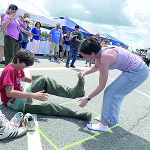 Eleanor Lynch helps cousin Owen O’Toole off with the waders in a relay at Wormfest in Wiscasset June 8. SUSAN JOHNS/Wiscasset Newspaper 